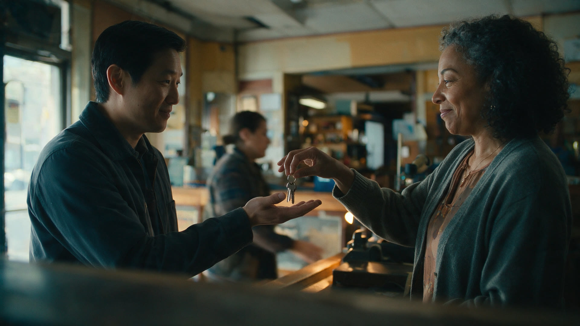 A person receives a set of keys handed across a counter at a repair shop